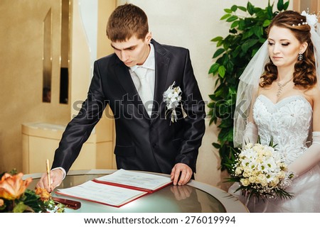 Wedding ceremony. Registry office. A newly-married couple signs the marriage document. Young couple signing wedding documents.