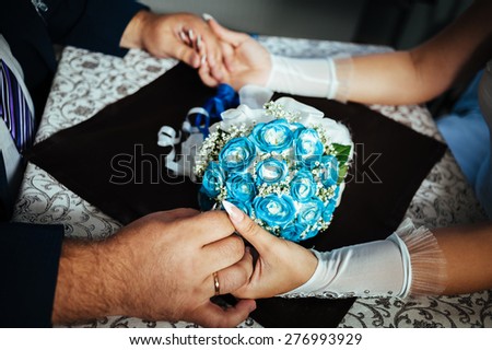 bride and groom are sitting at a table in restaurant. The groom's hand stroking his bride