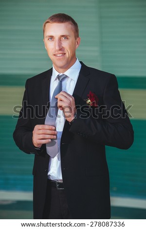 Portrait of handsome groom in the park getting ready for the wedding