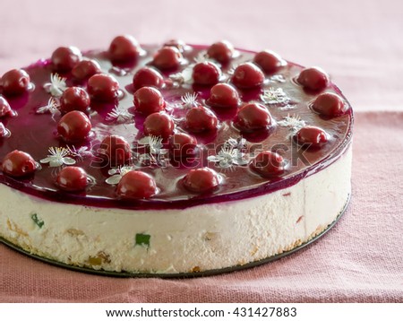 Cheese cake, decorated with flowers and cherry jelly