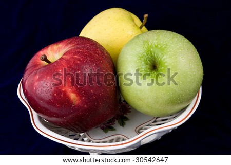Three apples in a vase, are photographed on a dark blue background