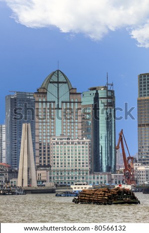 Barge on the Huangpu River in Shanghai transporting timber with modern buildings in the background