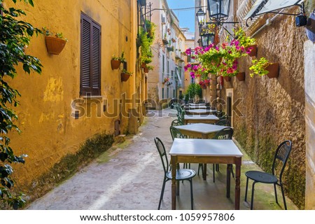 Cafe tables and chairs outside in old cozy street in the Positano town, Campania, Italy