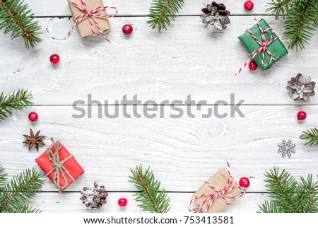 Christmas frame made of fir branches, red berries, gift boxes and pine cones on white wooden table. Christmas background. Flat lay. top view with copy space