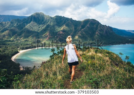 Blonde hiker looks over the ocean on a classic Hawaiian hike.
