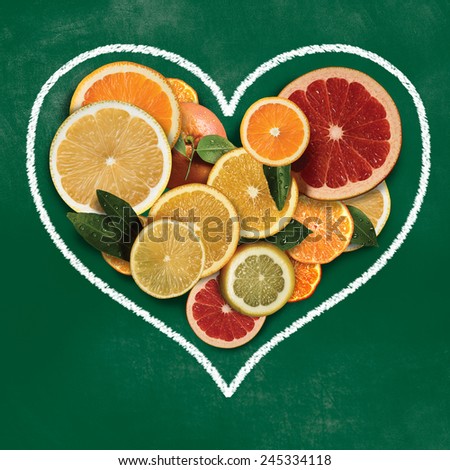 Mixed group of sliced citrus fruits on green board heart.