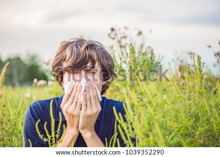 Young man sneezes because of an allergy to ragweed