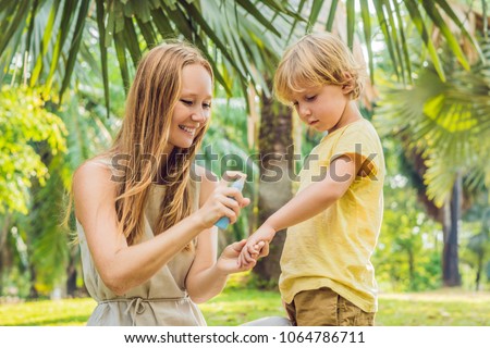 Mom and son use mosquito spray.Spraying insect repellent on skin outdoor