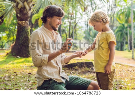 dad and son use mosquito spray.Spraying insect repellent on skin outdoor