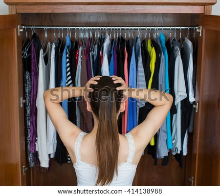 Frustrated young woman cannot decide what to wear from her closet
