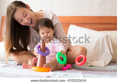 baby learning coordination skills while playing, and a happy proud mother watching her child with joy