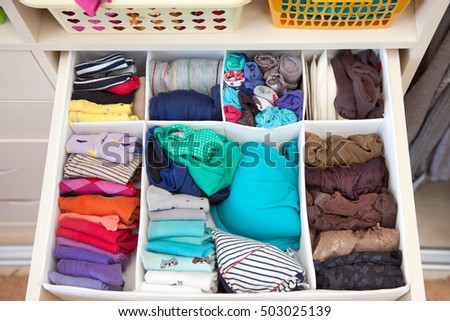 Women\'s clothing in the drawers of the wardrobe. Underwear, T-shirts and socks in the closet. Vertical storage.