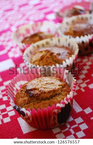Freshly baked muffins made with carrots and almonds in red paper cups on white and red background