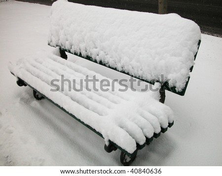 Snow covered bench in a winter day