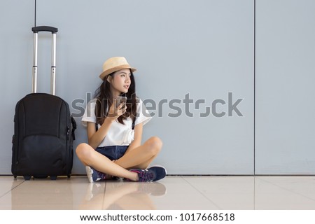 Asian woman teenager using smartphone at airport terminal sitting with luggage suitcase and backpack for travel in vacation summer relaxing waiting flight transport online check in or booking ticket