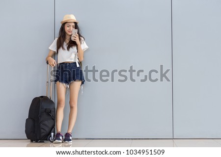 Asian woman teenager using smartphone at airport terminal standing with luggage suitcase and backpack for travel in vacation summer relaxing waiting flight transport online check in or booking ticket