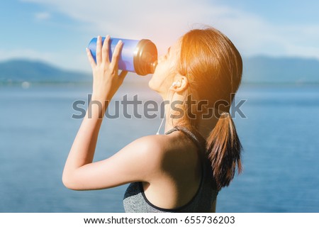 Young girl asian drinking protein shake with sport bra after exercise workout outdoor at beach seascape in summer for muscle building and slim fit body nice perfect
