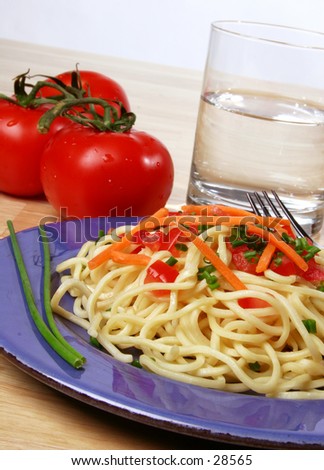 pasta dinner plate with noodles, tomato, carrots, and chives.