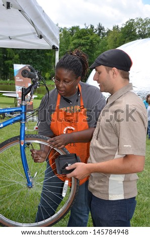ANN ARBOR, MI - JUNE 8: Common Cycle volunteer assists bicycle owner in bicycle maintenance at the Ann Arbor Mini Maker Faire June 8, 2013 in Ann Arbor, MI