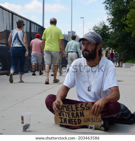 DETROIT, MI - JULY 6: Homeless veteran waits as people walk past him as he begs for money in Detroit, MI on July 6, 2014