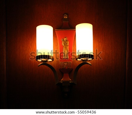 Vintage wall sconce in darkened room, with sculpture