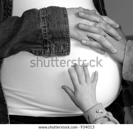 Black & White pregnant belly with Mom, Dad, and brothers hands.