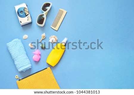 Summer cosmetic bag content. Blue terry towel, camera, sunglasses, wooden comb, toy sea horse and seashells. Flat lay photo, travel concept. Free space for text, mock-up