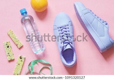 Water bottle, cereal energy bars, orange and purple sneakers on a pink background. Fitness food, workout, weight loss concept