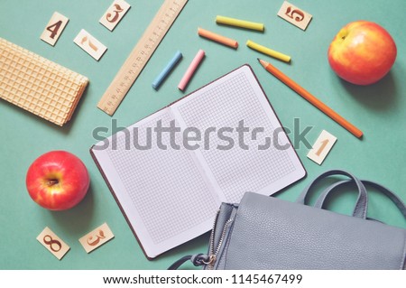 World Teachers\' Day greeting card. Flat lay photo red apples, waffles, ruler, wooden cards with  numbers, crayons and a backpack on a green table. Back to school concept