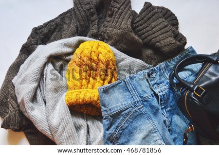 Women's clothes: a brown woolen cardigan, gray scarf, denim skirt and a yellow hat. Casual style. Autumn or winter outfit. Flat lay, top view photography