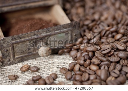 Antique coffee grinder filled with coffee beans and ground coffee - selective focus