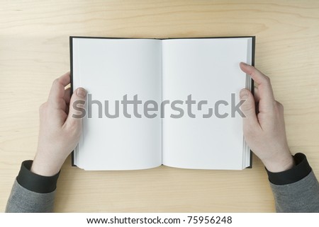 Young male reading an empty open book on a desk - insert your own message