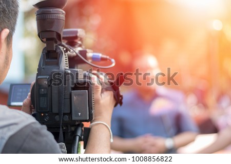 Behind the scene concept. Cameraman working on professional camera taking film interviewer interview celebrity people making news outdoors.