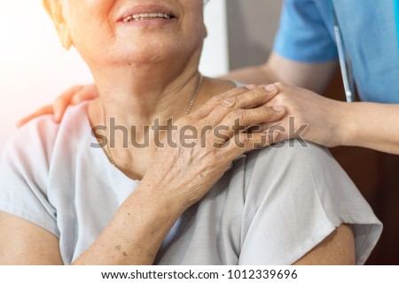 Elderly female hand holding hand of young caregiver at nursing home.Geriatric doctor or geriatrician concept. \
Doctor physician hand on happy elderly senior patient to comfort in hospital examination