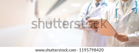Medical healthcare doctor team concept. Physicians in white gown and stethoscope, hand holding computer tablet on blur background corridor hospital for copy space.