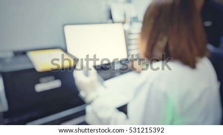 Blur abstract background of female scientist in white gown uniform working in university research laboratory.Blurry view of lab technologist work with computer data collection in lab room hospital.