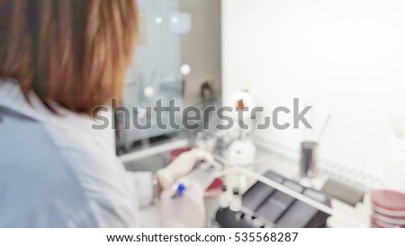 Blur abstract background female scientist workingon plate testing in university research laboratory.Blurry lab technologist writing on test drug resist in biosafety cabinet in science room in hospital