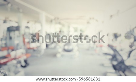 Blur abstract background of exercise equipments in in modern fitness gym. Blurry people work out in workout room.Defocus Fitness center with traineger equipments in vintage retro tone.