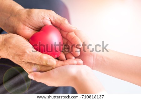 Philanthropy health care concept. Caregiver  with senior people hands with heart in palm in hospice center with copyspace.