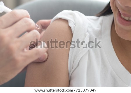Vaccine healthcare concept. Image of strong happy healthy Asia kid girl smiling getting vaccination with doctor pediatrician\'s hand holding medical syringe in hospital with lens flare effect.
