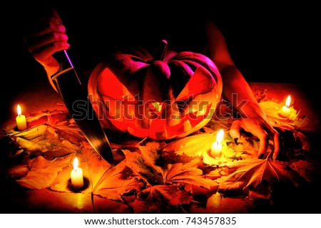 Halloween Pumpkin Jack O Lantern Halloween still life. Scary scene with knife, candles, and lights.