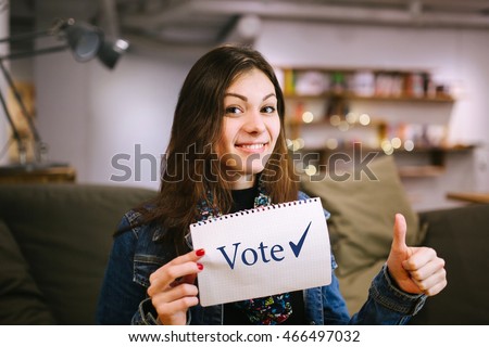 Young lady is agitating to vote in elections. Women brunette enjoys voting.\
Beautiful woman holding a sheet of paper with the \