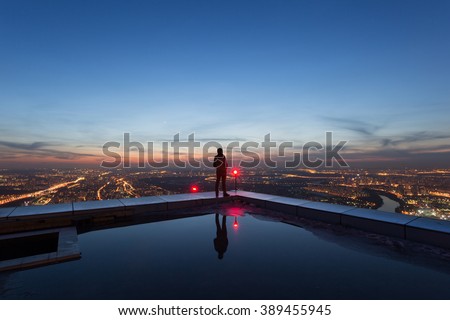 man on the edge of the roof of a skyscraper at night