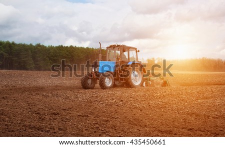 In the early,spring morning,because of the wood the bright sun ascends.The tractor goes and pulls a plow,plowing a field before landing of crops.On the earth dry stalks of a last year\'s sunflower lie.