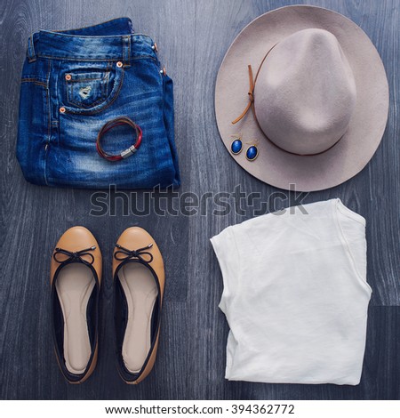Still Life of Outfit of Women. Casual jeans outfit with hat and white t-shirt on black wooden background.