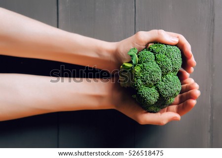 broccoli in hands. a wooden background. healthy eating concept.