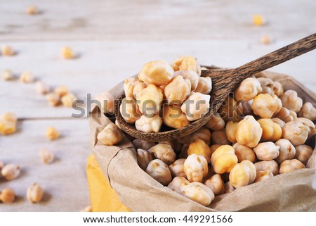 A wooden spoon of dried chickpeas on a chickpea bag.