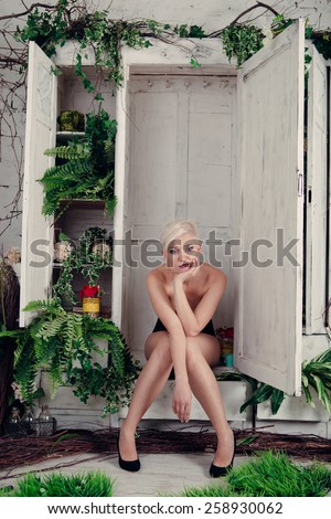 Naked blond woman is sitting in her closet. Concept : Nothing to wear