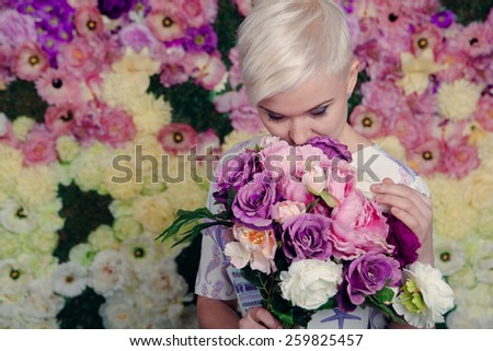 Beautiful blond woman holding flowers, looking up, short haircut