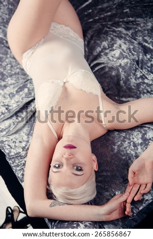 Beautiful naked woman in panties laying on bed. View from above. Blonde short haircut